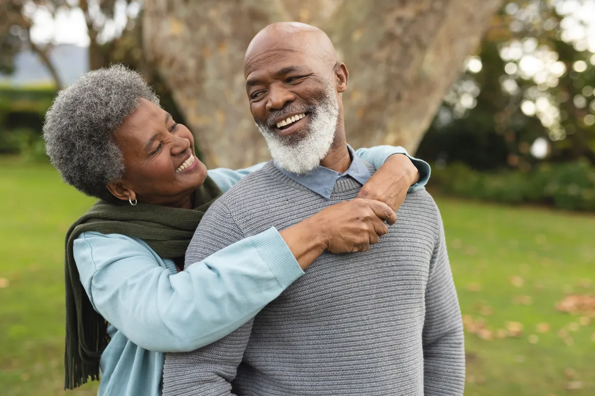 Smiling older couple embracing outdoors in a park.